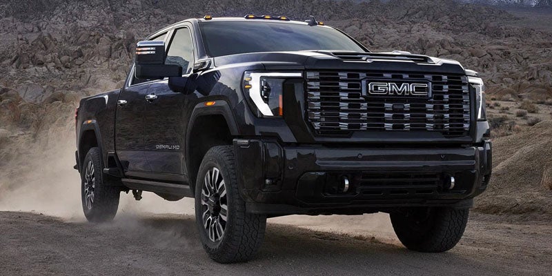 2026 GMC Sierra 2500 HD front grille view in Quincy IL navigating off-road terrain with rugged styling