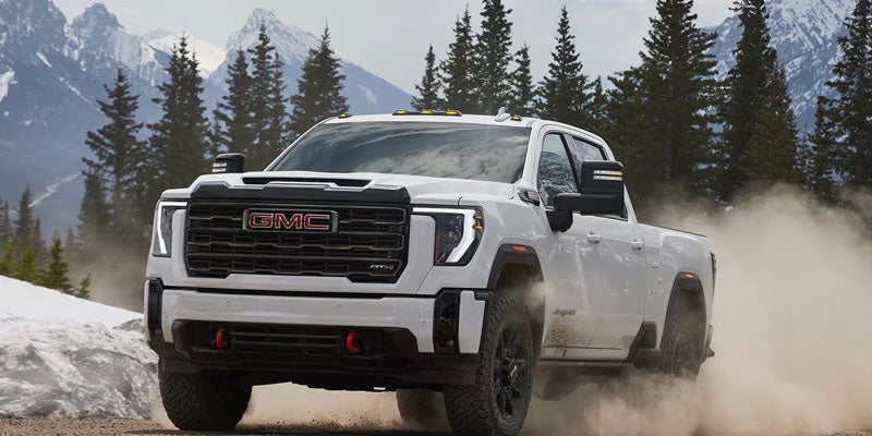 2026 GMC Sierra 2500 HD driving off-road near Quincy IL kicking up dust and showing AWD capability