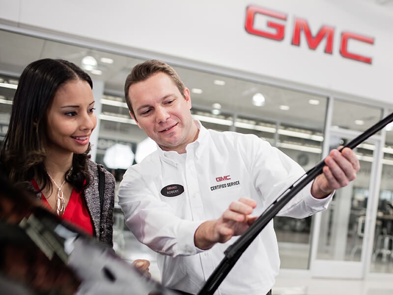 Man holding a car wiper, explaining to a girl
