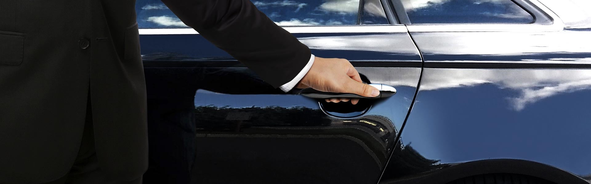 Person holding the handle of a black vehicle